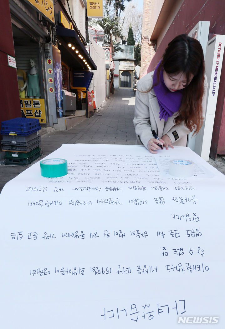 [서울=뉴시스] 김진아 기자 = 21일 서울 이태원역 1번 출구 앞 이태원참사 추모의 벽에서 10.29 이태원참사 희생자 유연주의 언니 유정이 2030 세대에게 호소하는 대자보를 작성하고 있다.  2024.03.21. bluesoda@newsis.com