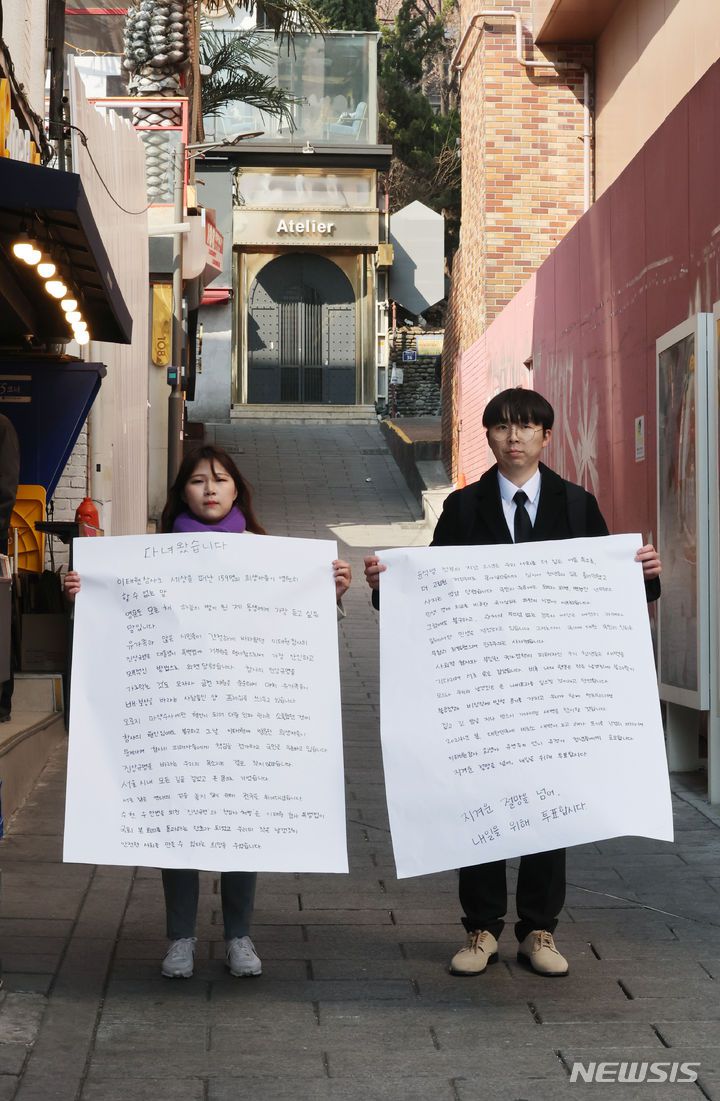 [서울=뉴시스] 김진아 기자 = 21일 서울 이태원역 1번 출구 앞 이태원참사 추모의 벽에서 10.29 이태원참사 희생자 유연주의 언니 유정이 2030 세대에게 호소하는 대자보를 작성한 뒤 들고있다.  2024.03.21. bluesoda@newsis.com