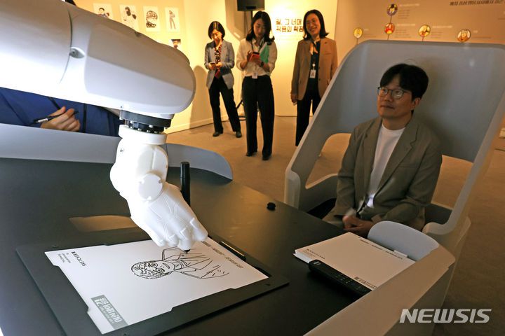 [서울=뉴시스] 박진희 기자 = 국립중앙도서관은 9일 서울 서초구 본관 전시실에서 열린 '이현세의 길 : K-웹툰 전설의 시작 특별전' 전시장에 인공지능 예술가 로봇 'Sketcher X'를 설치, 관람객 초상화를 그려주고 있다. 2024.05.09. pak7130@newsis.com