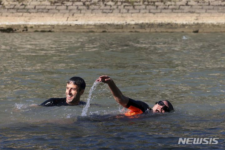 Paris Mayor Anne Hidalgo and Tony Estanguet, President of the Paris 2024 Olympic and Paralympic Games Organizing Committee, swim in the Seine river, Wednesday, July 17, 2024 in Paris. After months of anticipation, Paris Mayor Anne Hidalgo took a dip in the Seine River on Wednesday, fulfilling a promise she made months ago to show the river is clean enough to host open-swimming competitions during the 2024 Olympics ? and the opening ceremony on the river nine days away.(Joel Saget, Pool via AP)