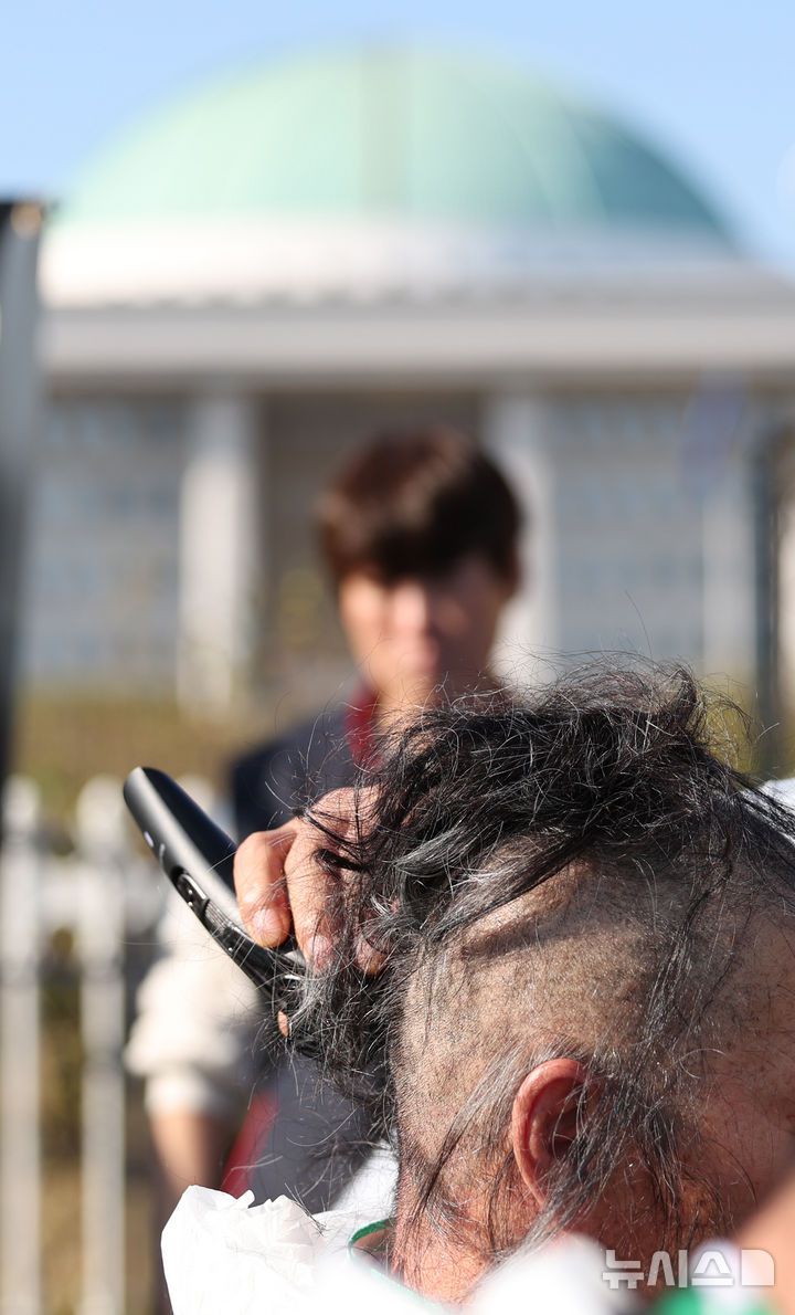 [서울=뉴시스] 김진아 기자 = 민주노총 공공운수노조 화물연대본부 조합원들이 11일 서울 여의도 국회 앞에서 '국민안전 사수! 안전운임제 입법 촉구! 화물노동자 100인 삭발 결의대회에서 삭발식을 하고 있다. 2024.11.11. photo@newsis.com