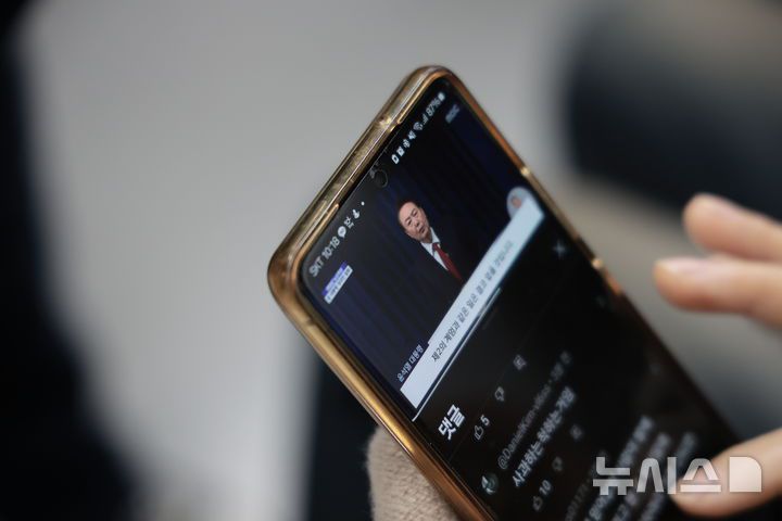 [서울=뉴시스] 정병혁 기자 = 7일 서울 서대문구 지하철 3호선 열차에서 한 시민이 윤석열 대통령의 대국민담화를 시청하고 있다. 2024.12.07. jhope@newsis.com