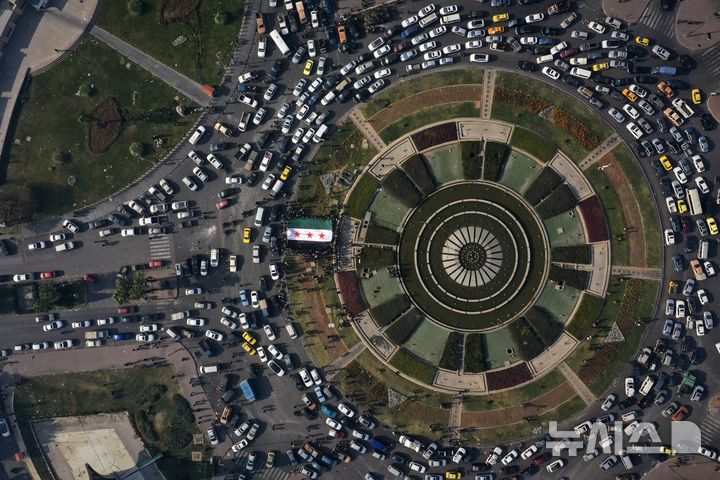 [다마스쿠스=AP/뉴시스] 지난 9일(현지시각) 시리아 다마스쿠스 우마이야 광장에서 시민들이 대형 혁명기를 들고 바샤르 알아사드 정권의 붕괴를 축하하고 있다. 2024.12.17.