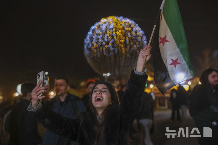 [다마스쿠스=AP/뉴시스] 지난 22일(현지시각) 시리아 다마스쿠스의 한 광장에서 열린 크리스마스 축하 콘서트에서 한 여성이 혁명기를 흔들며 즐기고 있다. 2024.12.26.