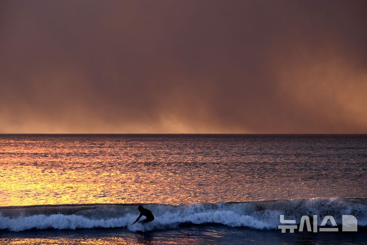 [산타모니카=AP/뉴시스] 7일(현지시각) 미국 캘리포니아주 산타모니카 해변 하늘이 퍼시픽 팰리세이즈 화재로 검붉게 타고 있다. 2025.01.08.
