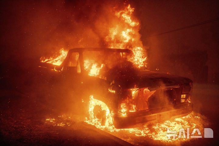 [알타데나=AP/뉴시스] 8일(현지시각) 미 캘리포니아주 알타데나에서 발생한 '이튼 파이어' 산불로 자동차 한 대가 불에 타고 있다. 2025.01.09.