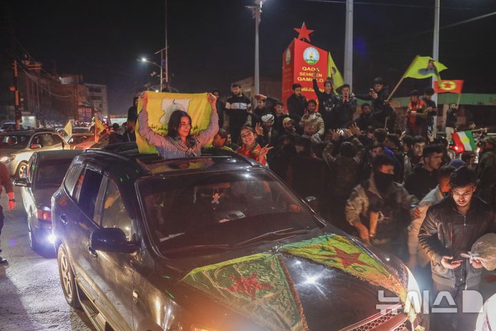 [카미실리=AP/뉴시스] 10일(현지 시간) 시리아 북동부 카미실리에서 주민들이 시리아 과도정부와 북동부 지역을 장악한 시리아민주군(SDF) 간 역사적인 협정 체결을 축하하고 있다. 앞서 아마드 알샤라 시리아 과도정부 대통령과  마즐룸 압디 SDF 사령관은 두 세력을 통합하는 합의서에 서명했다. 2025.03.12.