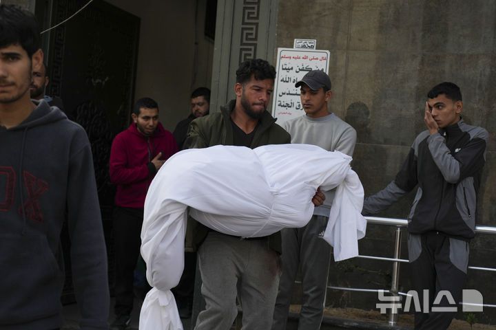 [가자지구=AP/뉴시스] 18일(현지 시간) 가자지구 가자시티 시파 병원에서 팔레스타인인들이 이스라엘군 공습으로 숨진 희생자의 시신을 옮기고 있다. 2025.03.18.