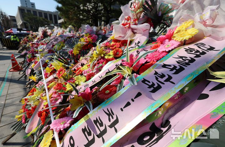 [서울=뉴시스] 이영환 기자 = 윤석열 대통령 탄핵심판 선고가 예상보다 늦어지고 있는 19일 오전 서울 종로구 헌법재판소 앞에 윤 대통령 지지자들이 보낸 화환이 놓여 있다.헌법재판소 사무처장이 지난 달 26일까지 자진 정비를 요청하며 적치물 정비 예고통지서를 부착했지만 화환은 방치되고 있다. 2025.03.19. 20hwan@newsis.com