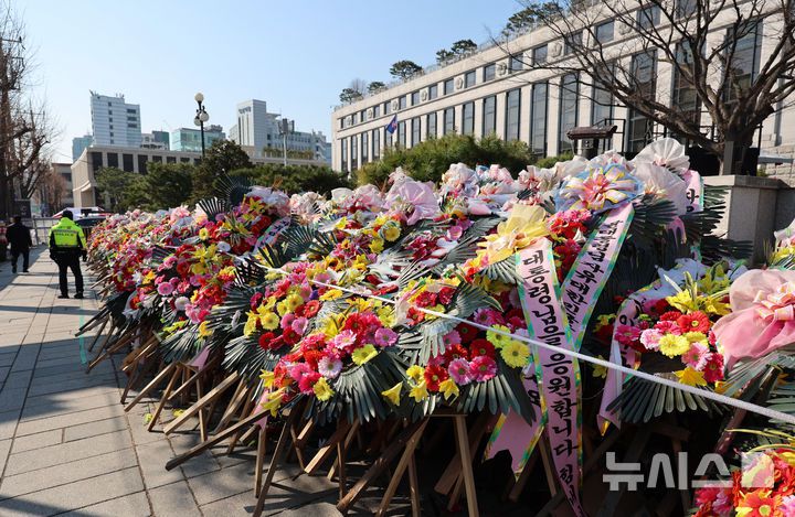 [서울=뉴시스] 이영환 기자 = 윤석열 대통령 탄핵심판 선고가 예상보다 늦어지고 있는 19일 오전 서울 종로구 헌법재판소 앞에 윤 대통령 지지자들이 보낸 화환이 놓여 있다.헌법재판소 사무처장이 지난 달 26일까지 자진 정비를 요청하며 적치물 정비 예고통지서를 부착했지만 화환은 방치되고 있다. 2025.03.19. 20hwan@newsis.com