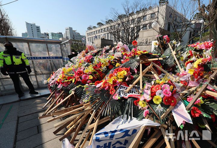 [서울=뉴시스] 이영환 기자 = 윤석열 대통령 탄핵심판 선고가 예상보다 늦어지고 있는 19일 오전 서울 종로구 헌법재판소 앞에 윤 대통령 지지자들이 보낸 화환이 놓여 있다.헌법재판소 사무처장이 지난 달 26일까지 자진 정비를 요청하며 적치물 정비 예고통지서를 부착했지만 화환은 방치되고 있다. 2025.03.19. 20hwan@newsis.com