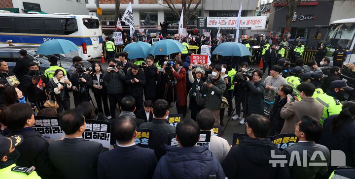 [서울=뉴시스] 홍효식 기자 = 윤석열 대통령 탄핵 심판 선고 발표가 늦어지고 있는 20일 오전 서울 종로구 헌법재판소 앞에서 경찰들이 탄핵 반대 시위자의 음식물 투척을 막기 위해 우산을 펼쳐들고 있다. 2025.03.20. yesphoto@newsis.com