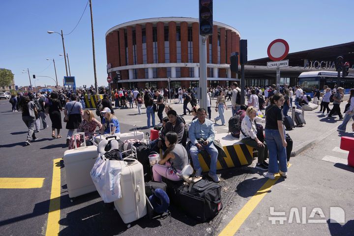 [마드리드=AP/뉴시스] 28일(현지 시간) 스페인에서 대규모 정전 사태가 발생한 가운데 마드리드 아토차역 앞에 승객들이 앉아 있다. 2025.04.29.