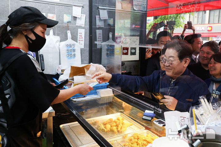 [포천=뉴시스] 조성우 기자 = 이재명 대통령이 대선 후보이던 지난달 1일 오후 경기 포천시 신읍사거리 인근에서 골목골목 경청투어를 열고 치킨을 맛본 뒤 지역상품권으로 결제하고 있다. 2025.05.01. xconfind@newsis.com