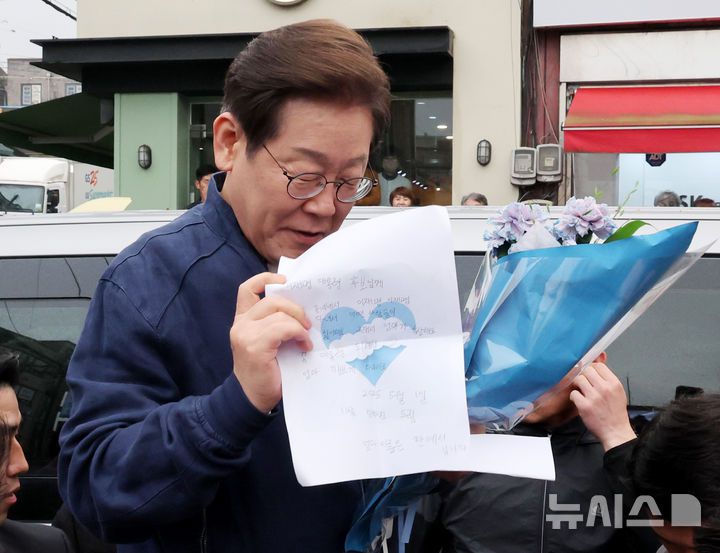 [연천=뉴시스] 조성우 기자 = 골목골목 경청투어에 나선 이재명 더불어민주당 대선후보가 1일 오후 경기도 연천군 전곡읍 인근에서 시민들과 인사를 하던 중 어린이가 이 후보에게 쓴 편지를 읽고 있다. 2025.05.01. xconfind@newsis.com