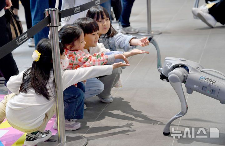 [광주=뉴시스] 변재훈 기자 = 어린이날인 5일 오후 광주 동구 국립아시아문화전당 어린이문화원 일대에서 열린 어린이·가족문화축제 하우 펀(HOW FUN)11 행사장에서 어린이들이 로봇 강아지를 향해 손 내밀고 있다. 2025.05.05. wisdom21@newsis.com