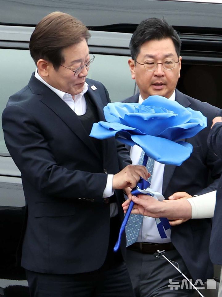 [여주=뉴시스] 조성봉 기자 = 민심을 청취하는 '경청 투어'에 나선 이재명 더불어민주당 대선후보가 5일 경기 여주시 구양리 새마을식당 앞에서 지지자에게 파란색 종이 장미를 선물받고 있다.2025.05.05. suncho21@newsis.com