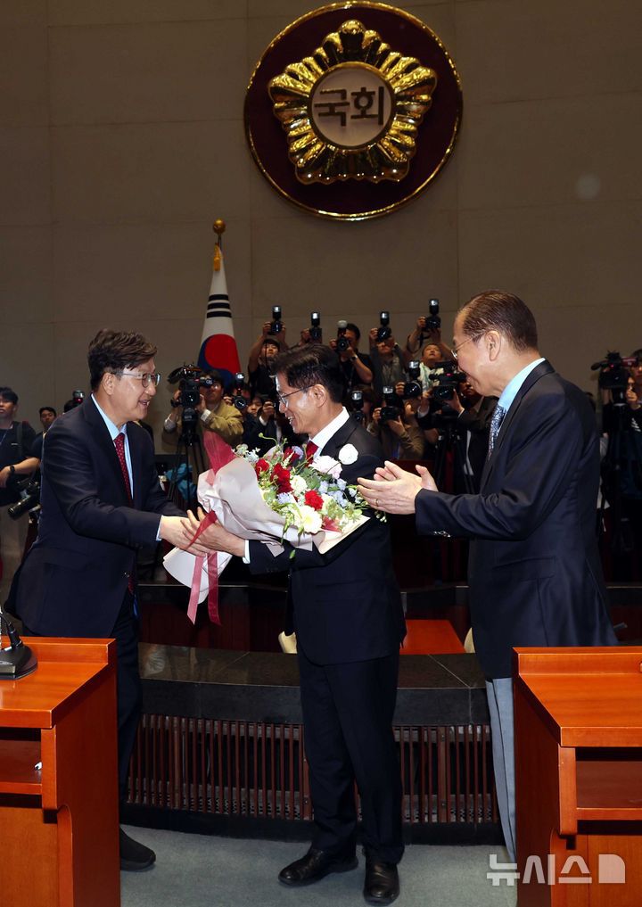 [서울=뉴시스] 조성봉 기자= 김문수 국민의힘 대선후보가 9일 서울 여의도 국회에서 열린 의원총회에서 권성동 원내대표에게 꽃다발을 받고 있다. 오른쪽은 권영세 비대위원장. 2025.05.09. suncho21@newsis.com