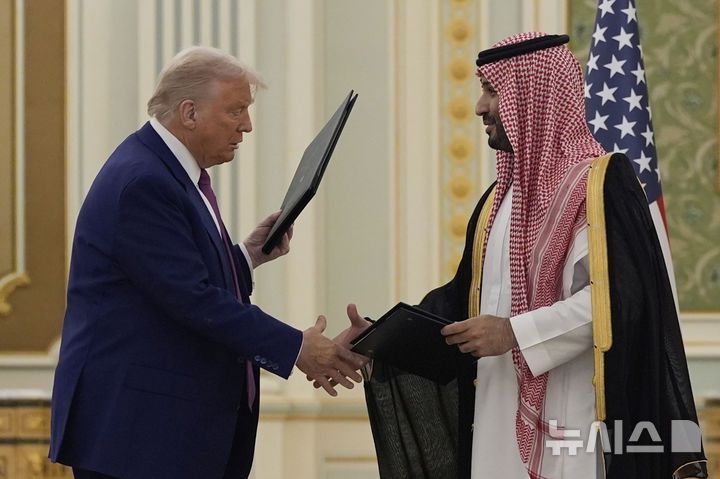 [리야드=AP/뉴시스] 도널드 트럼프(왼쪽) 미국 대통령과 무함마드 빈 살만 사우디아라비아 왕세자가 지난 13일(현지 시간) 리야드 왕궁에서 열린 협정서 서명식을 마치고 이를 교환하며 악수하고 있다. 2025.05.16.