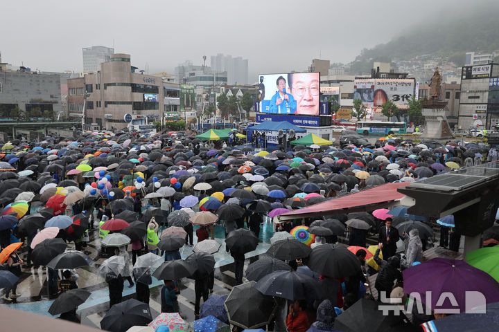 [여수=뉴시스] 권창회 기자 = 이재명 더불어민주당 대선 후보가 15일 전남 여수시 이순신광장에서 열린 집중유세에서 연설을 하는 가운데 시민들이 우산을 쓰고 이 후보 연설을 듣고 있다. (공동취재) 2025.05.15. photo@newsis.com