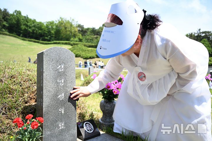 [광주=뉴시스] 김혜인 기자 = 광주5·18민주화운동 45주년 기념식이 열린 18일 오전 광주 북구 운정동 국립 5·18민주묘지에서 5·18희생자의 아내가 남편 김영철 열사의 묘역을 찾아 묘비를 닦고 있다. 2025.05.18. hyein0342@newsis.com