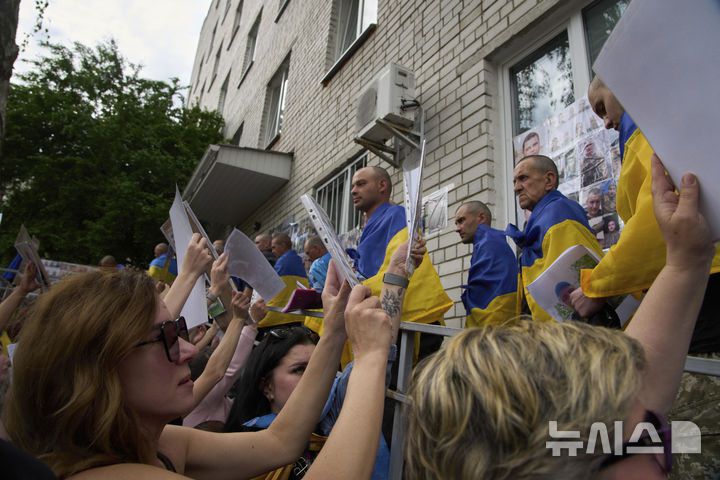 [AP/뉴시스] 전선서 실종된 우크라 병사들의 가족들이 25일 교환석방돼 돌아온 우크라 전쟁포로들에게 사진을 들어보이며 가족 소식을 애타게 찾고 있다.