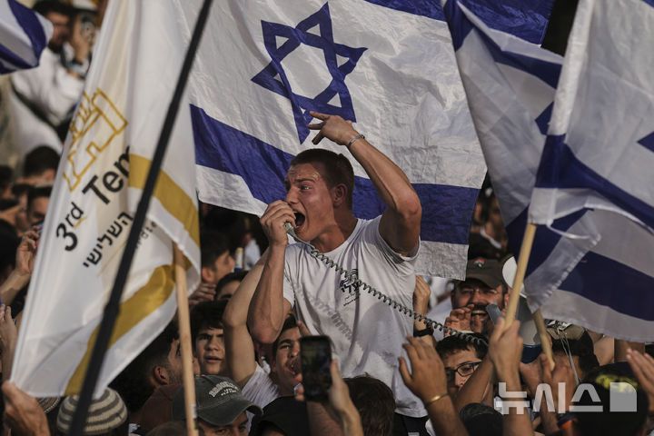 [예루살렘=AP/뉴시스]5월 26일 예루살렘에서 연례 '예루살렘의 날' 행사가 열려 이스라엘 사람들이 국기를 흔들며 '국기 행진'을 하고 있다.  올해로 58주년을 맞은 '예루살렘의 날'은 1967년 이스라엘이 중동전쟁을 일으켜 서안지구, 가자지구와 동예루살렘 까지 점령한 것을 기념하는 국경일이다. 2025.06.01.