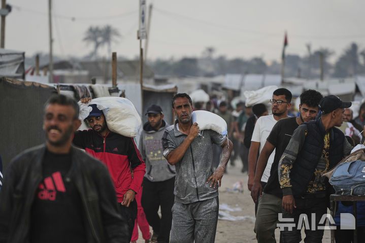 [칸유니스=AP/뉴시스] 3일(현지 시간) 가자지구 칸유니스에서 팔레스타인 주민들이 '가자 인도주의 재단'이 배급한 식량을 얻어 돌아가고 있다. 2025.06.04.