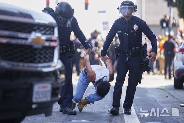 [로스앤젤레스=AP/뉴시스] 8일(현지 시간) 미 캘리포니아주 로스앤젤레스 도심에서 이민세관단속국(ICE)의 불법 이민자 단속 및 체포에 항의하던 시위 참가자가 경찰에 체포되고 있다. 도널드 트럼프 대통령은 불법 이민자 단속에 항의하는 시위에 참여하는 사람들은 마스크를 착용해서는 안 된다고 밝혔다. 2025.06.09.