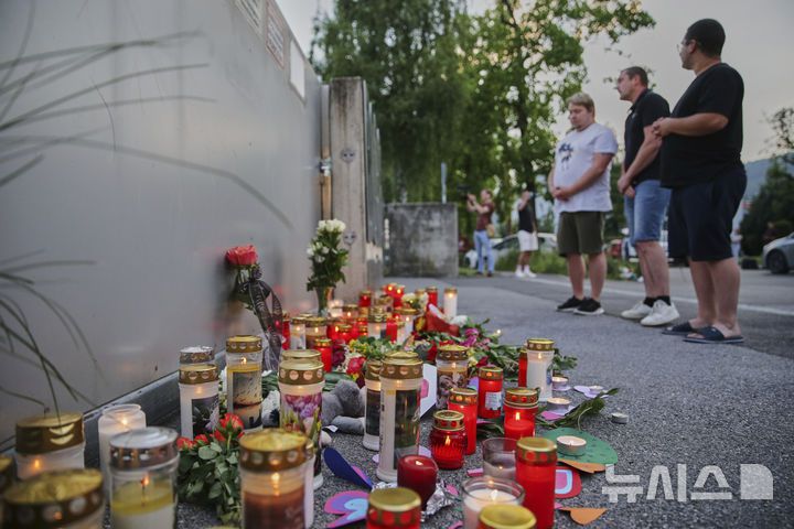 [그라츠=AP/뉴시스] 10일(현지 시간) 오스트리아 그라츠의 한 고등학교에서 총기 난사 사건이 발생한 후 한 남성이 학교 입구에 희생자를 추모하는 꽃과 초가 놓여져 있다. 2025.06.11.