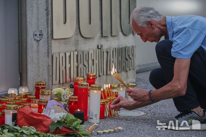 [그라츠=AP/뉴시스] 10일(현지 시간) 오스트리아 그라츠의 한 고등학교에서 총기 난사 사건이 발생한 후 한 남성이 학교 입구에서 희생자를 위한 촛불을 켜고 있다. 2025.06.11.