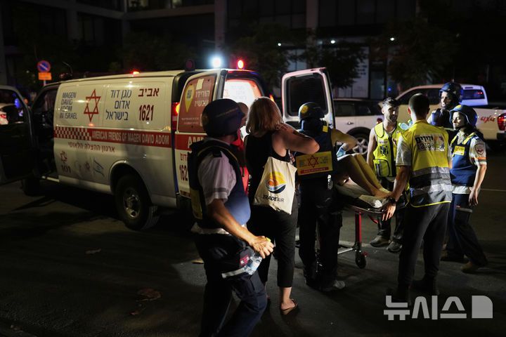 [텔아비브=AP/뉴시스] 13일(현지 시간) 이스라엘 텔아비브에서 구급대원들이 이란이 발사한 미사일에 맞은 건물에서 부상자를 대피시키고 있다. 2025.06.14.