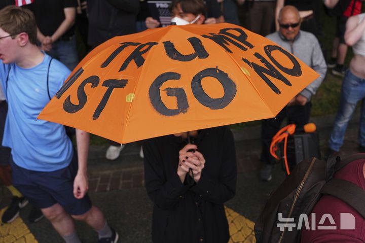 [워싱턴=AP/뉴시스] 미국 워싱턴에서 육군 창설 250주년 기념 대규모 열병식이 열린 가운데 일부 시위 참가자들이 트럼프 반대 문구가 새겨진 우산을 들고 나왔다. 2025.06.15.