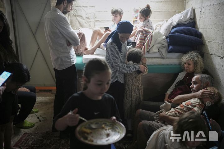 [예루살렘=AP/뉴시스] 15일(현지 시간) 예루살렘에 이란의 미사일 경보가 발령돼 지하 대피소에 가족과 함께 대피한 소녀가 음식을 먹고 있다. 2025.06.16.