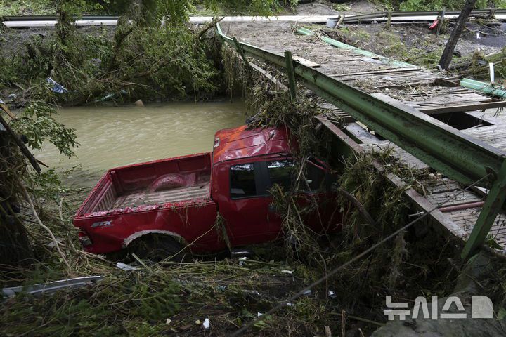 [밸리 그로브=AP/뉴시스] 지난 6월16일 미 웨스트버지니아주 밸리 그로브에서 홍수에 떠내려가던 픽업 트럭 한 대가 교량에 박혀 멈춰 서 있다. 돌발홍수도 토네이도처럼 실시간 경보가 필요하다고 미 당국은 말하고 있다. 2025.07.06.