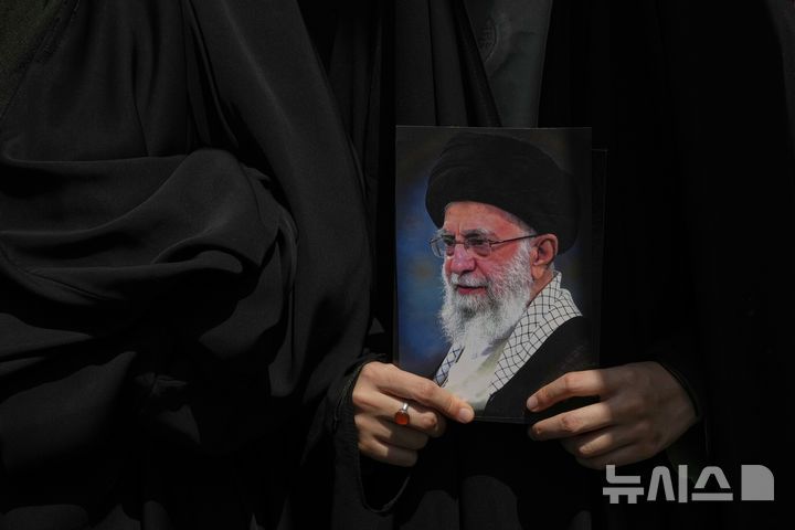 [테헤란=AP/뉴시스] 지난 20일(현지 시간) 이란 테헤란에서 열린 이스라엘의 공습 규탄 시위에서 한 참가자가 아야톨라 알리 하메네이 최고지도자의 사진을 들고 있다. 2025.06.23.