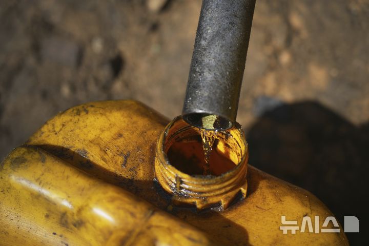 [가자시티=AP/뉴시스] 지난 22일(현지 시간) 가자지구 가자시티 남쪽 시로드에서 팔레스타인 청년이 플라스틱을 녹여 만든 연료를 연료통에 모으고 있다. 팔레스타인 청년들은 플라스틱 폐기물을 금속 드럼에 넣고 가열해 만든 연료를 병에 담아 판매하며, 이는 현지에서 발전기나 이동용 연료로 사용된다. 유독한 연기와 불길에 노출되는 고된 작업이지만, 이들에게는 가족의 생계를 이어가는 거의 유일한 수단이다. 2025.06.25.