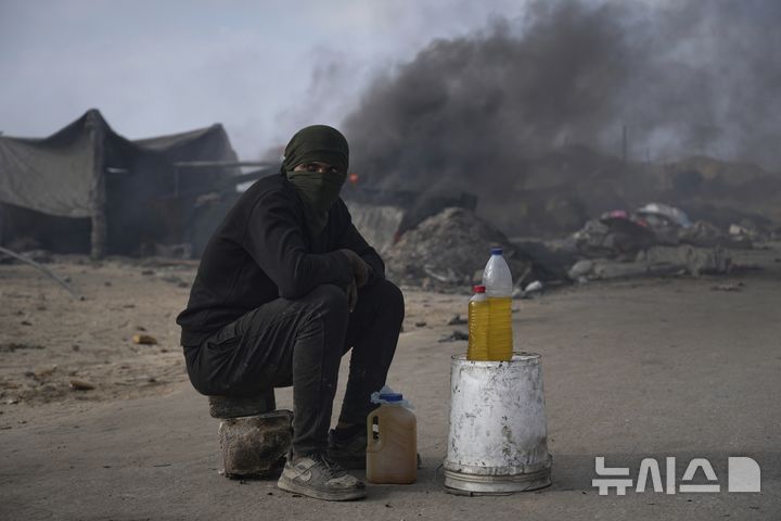 [가자시티=AP/뉴시스] 지난 22일(현지 시간) 가자지구 가자시티 남쪽 시로드에서 팔레스타인 청년이 플라스틱에서 추출한 연료를 판매하고 있다. 팔레스타인 청년들은 플라스틱 폐기물을 금속 드럼에 넣고 가열해 만든 연료를 병에 담아 판매하며, 이는 현지에서 발전기나 이동용 연료로 사용된다. 유독한 연기와 불길에 노출되는 고된 작업이지만, 이들에게는 가족의 생계를 이어가는 거의 유일한 수단이다. 2025.06.25.