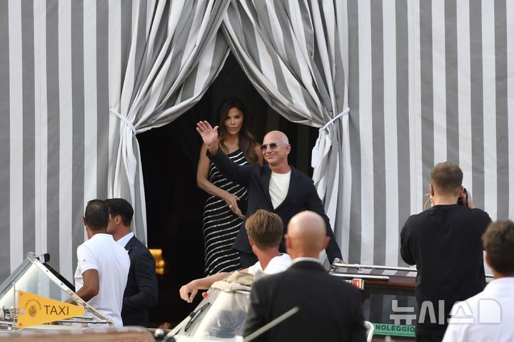 [베네치아=AP/뉴시스] 아마존 창업자 제프 베이조스(오른쪽)와 약혼녀 로런 산체스가 25일(현지 시간) 이탈리아 베네치아의 한 호텔에서 나오고 있다. 베이조스가 베네치아에서 초호화 결혼식을 계획했지만, 혼잡을 우려한 현지 시민들의 거센 반발에 장소 변경을 검토 중인 것으로 알려졌다. 두 사람은 26일부터 28일까지 사흘간 베네치아에서 결혼식을 올릴 예정이었다. 2025.06.26.