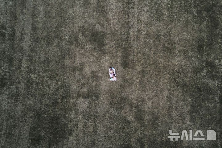 [프랑크푸르트=AP/뉴시스] 1일(현지 시간) 독일 프랑크푸르트 한 공원에서 한 여성이 무더운 날씨 속 메마른 풀밭에 누워 일광욕을 하고 있다. 2025.07.02.