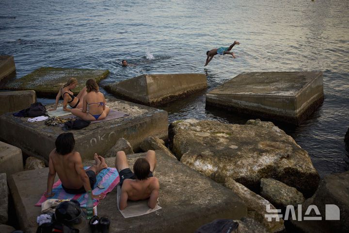 [바르셀로나=AP/뉴시스] 스페인에 무더위가 이어진 1일(현지 시간) 바르셀로나 해변을 찾은 시민들이 물놀이와 일광욕을 즐기고 있다. 2025.07.02.