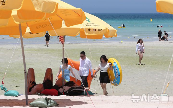 [제주=뉴시스] 우장호 기자 = 무더위가 기승을 부린 3일 오후 제주시 한림읍 협재해수욕장을 찾은 피서객들이 바닷물에 발을 담그며 더위를 식히고 있다. 기상청은 이날 제주 지역 장마가 사실상 지난달 26일 종료됐다고 발표했다. 올해 제주 장마 기간은 지난달 12~26일로 2주간이었으며, 이는 기상 관측 사상 가장 일찍 종료된 장마로 기록됐다. 2025.07.03. woo1223@newsis.com