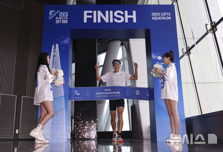 [서울=뉴시스] 김근수 기자 = 6일 오전 서울 송파구 롯데월드타워 일대에서 열린 '2025 롯데 아쿠아슬론'에서 참가자가 결승점을 통과하고 있다. 철인 3종 경기에서 사이클론을 제외한 오픈워터 수영과 마라톤을 함께 겨루는 '2025 롯데 아쿠아슬론'은 석촌호수 두 바퀴(총 1.5Km)를 완영 후, 롯데월드타워 1층부터 123층까지 2,917개의 계단을 오르는 수직 마라톤 스카이런(SKY RUN)으로 진행됐다. 2025.07.06. ks@newsis.com