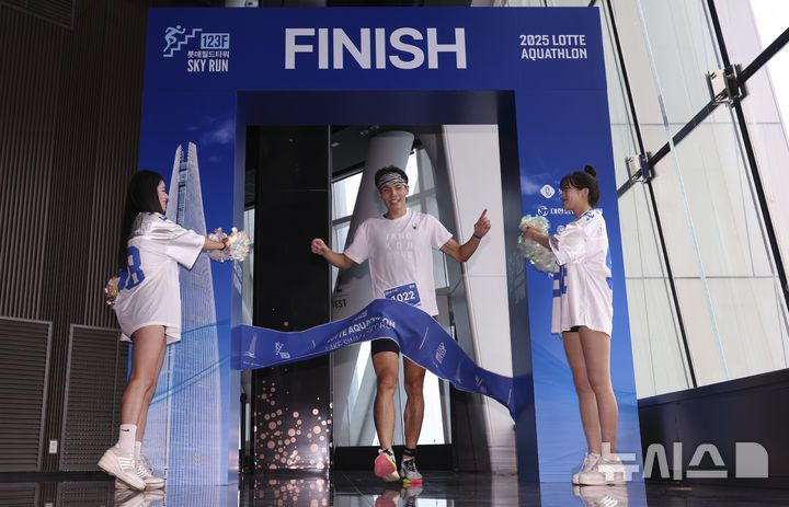[서울=뉴시스] 김근수 기자 = 6일 오전 서울 송파구 롯데월드타워 일대에서 열린 '2025 롯데 아쿠아슬론'에서 참가자가 결승점을 통과하고 있다. 철인 3종 경기에서 사이클론을 제외한 오픈워터 수영과 마라톤을 함께 겨루는 '2025 롯데 아쿠아슬론'은 석촌호수 두 바퀴(총 1.5Km)를 완영 후, 롯데월드타워 1층부터 123층까지 2,917개의 계단을 오르는 수직 마라톤 스카이런(SKY RUN)으로 진행됐다. 2025.07.06. ks@newsis.com