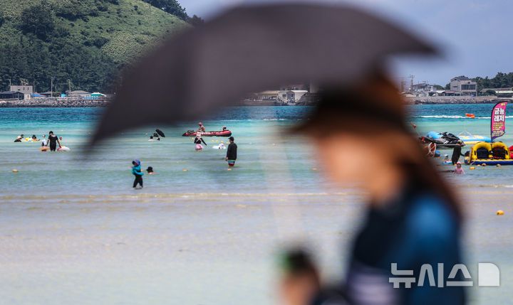 [제주=뉴시스] 우장호 기자 = 폭염의 기세가 수그러들지 않는 6일 오후 제주시 한림읍 금능해수욕장을 찾은 피서객들이 시원한 바닷물에 발을 담그며 더위를 식히고 있다. 2025.07.06. woo1223@newsis.com