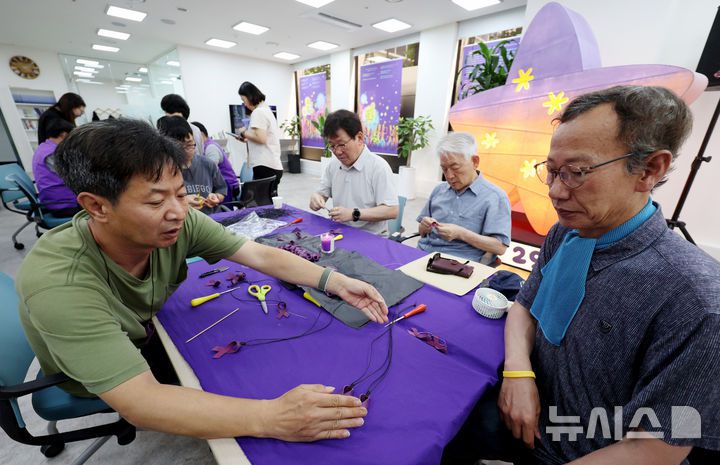 [서울=뉴시스] 김진아 기자 = 10·29 이태원참사 유가족협의회·시민대책회의를 비롯한 참석자들이 12일 서울 종로구 별들의집에서 열린 10.29 이태원 참사, 함께 만드는 1000일 '1000개의 별목걸이 함께 만들어요'에서 보라리본 목걸이를 만들고 있다. 2025.07.12. bluesoda@newsis.com