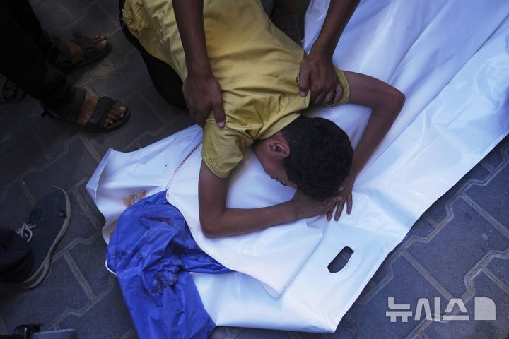 [누세이라트=AP/뉴시스] 13일(현지 시간) 가자지구 중부 누세이라트 알 아우다 병원에서 한 소년이 식수 배급을 받다 이스라엘군의 공습으로 사망한 친구의 시신을 안고 있다. 2025.07.14.