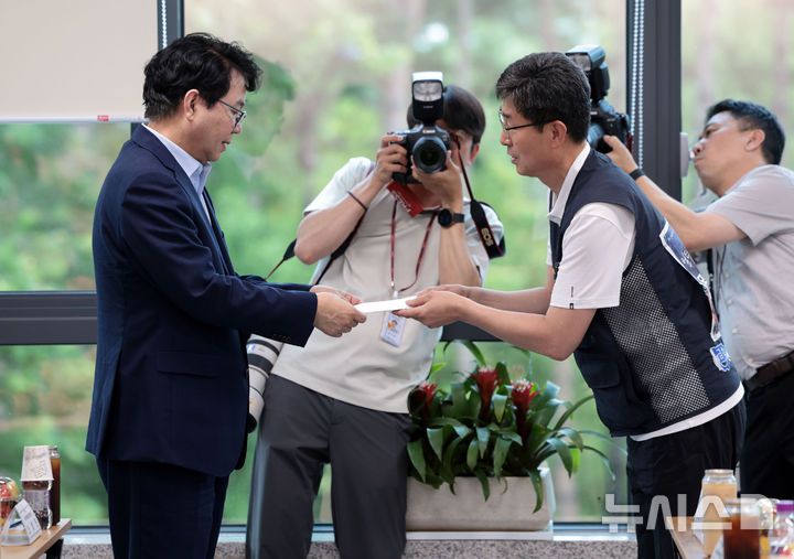 [서울=뉴시스] 김명원 기자 = 이한주(왼쪽) 국정기획위원장이 18일 서울 종로구 정부서울청사 창성동 별관 국정기획위원회에서 열린 지난 정부 노동정책으로 희생된 유족과 국정기획위원회의 간담회에서 김정욱 금속노조 쌍용자동차지부 법규실장으로부터 이재명 대통령에게 보내는 편지를 전달 받고 있다. (공동취재) 2025.07.18. photo@newsis.com