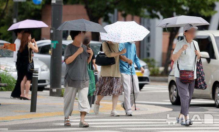 [서울=뉴시스] 조성우 기자 = 서울에 일주일째 폭염경보가 이어지는 30일 서울 시내의 한 거리에서 시민이 양산을 쓰고 이동하고 있다. 2025.07.30. xconfind@newsis.com