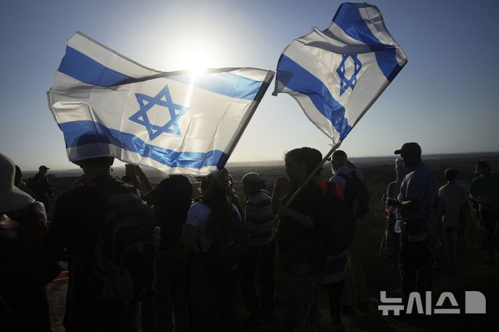 [이스라엘 남부=AP/뉴시스]  이스라엘이 가자 점령 선언 후에도 또 서안지구의 정착촌 3041세대 증축을 8월 13일 발표했다.  사진은 7월 30일 가자지구 접경 지역에서 이스라엘 극우 활동가들이 국기를 들고 유대인 정착촌 재건 촉구 행진을 하는 장면. 2025.08.14.